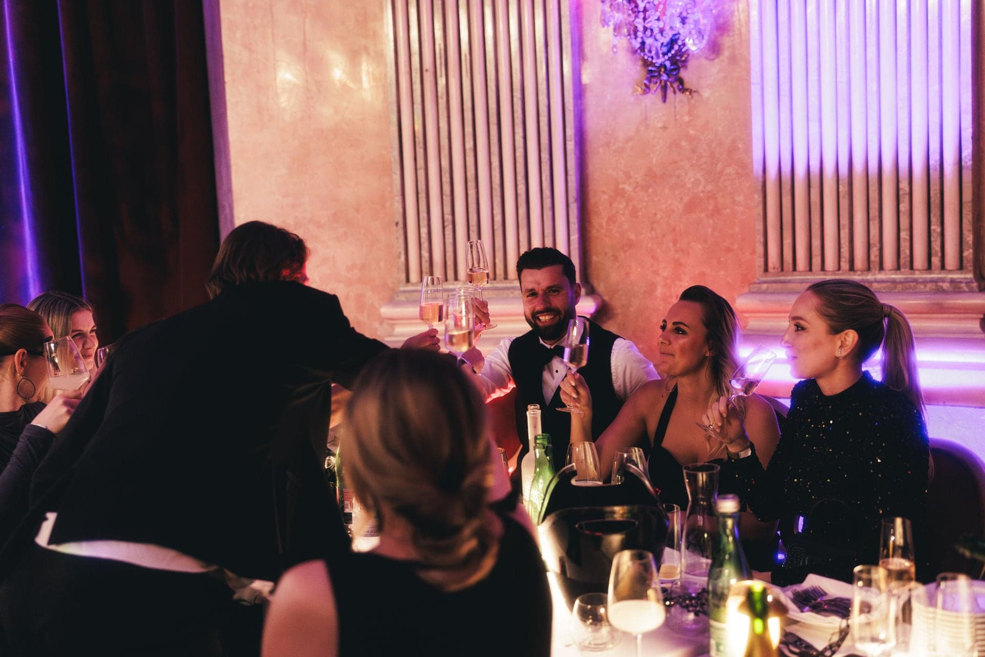 Ballgäste im Gespräch am Tisch, sie stoßen mit Sekt an