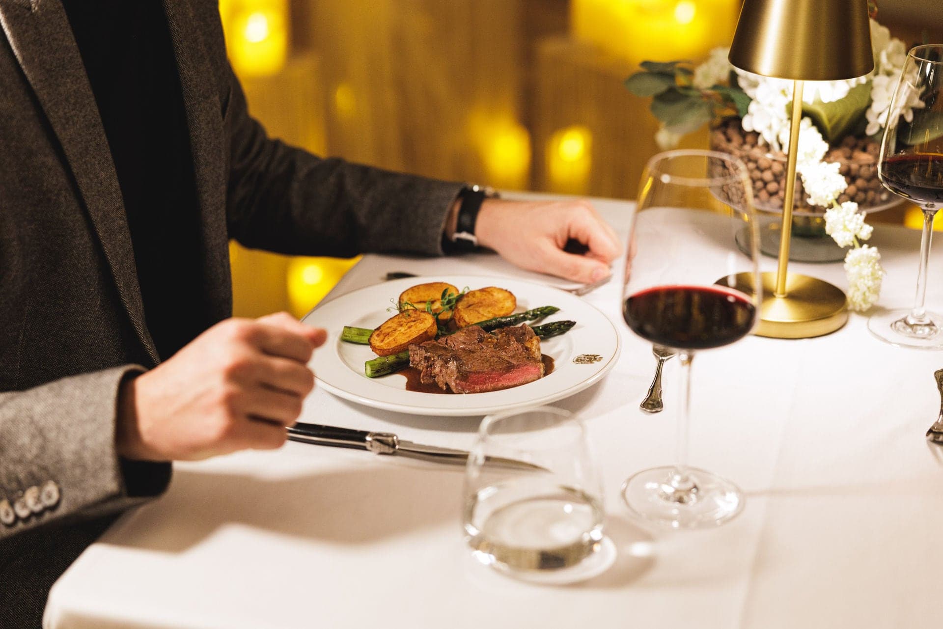Gast am gedeckten Tisch mit Rindsfilet und einem Glas Rotwein