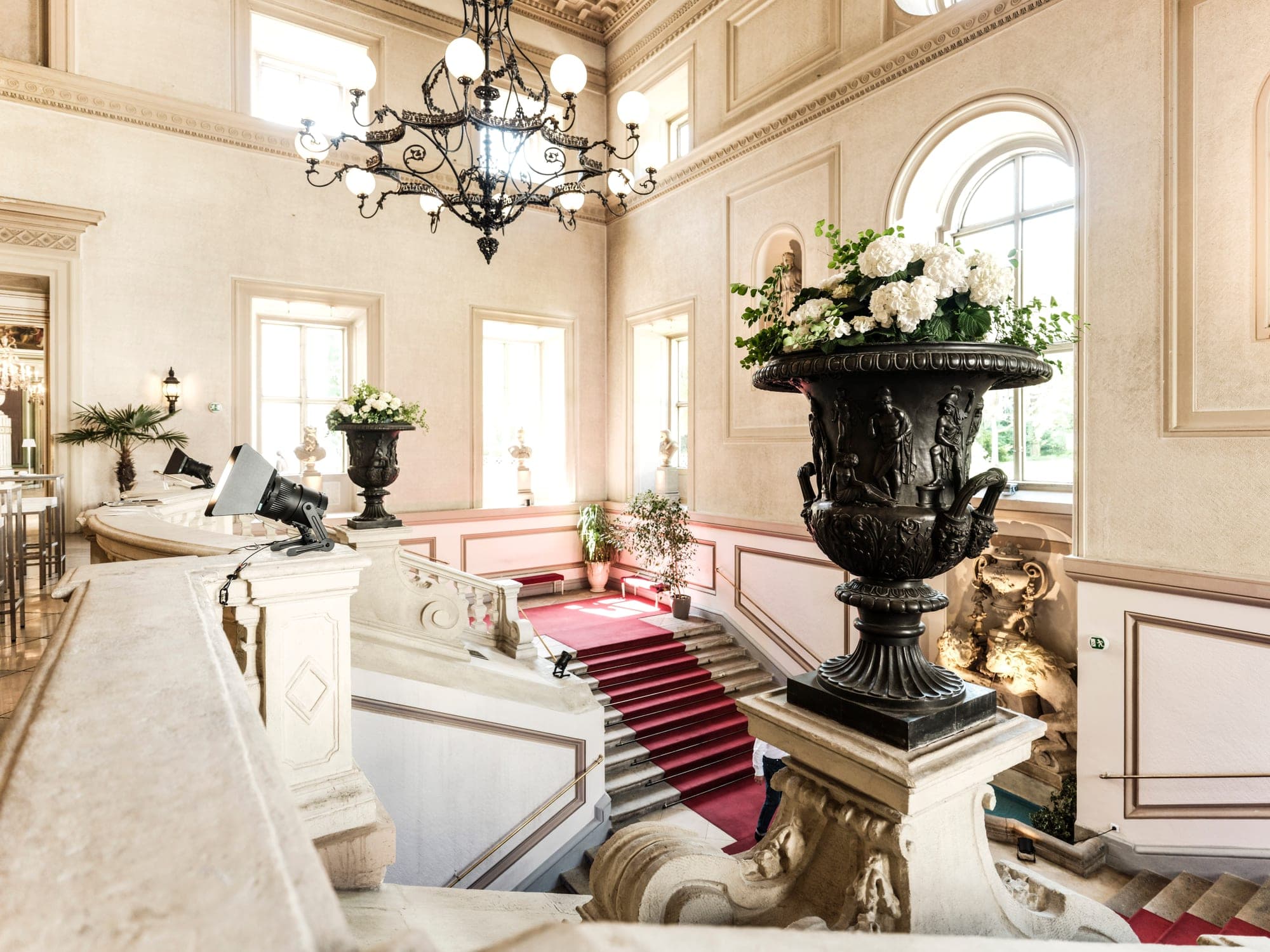 Feststiege des Palais Auersperg mit rotem Teppich, Luster und Blumenvase