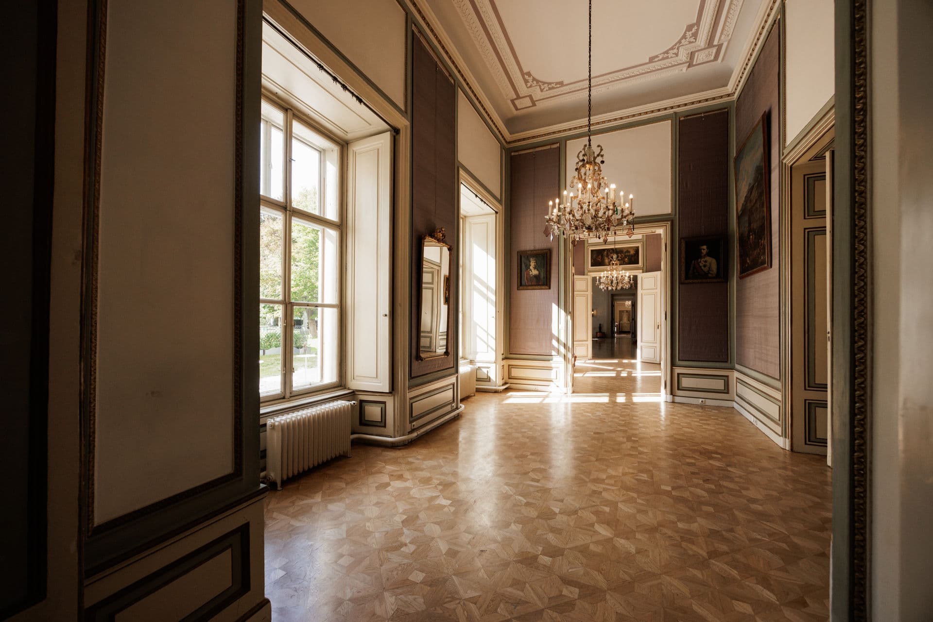 Leerer Salon mit Parkett, Luster und hohen Flügeltüren